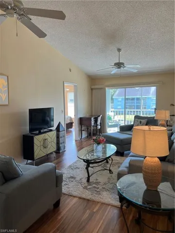 Vaulted ceiling featuring two ceiling fans and wood-finish flooring