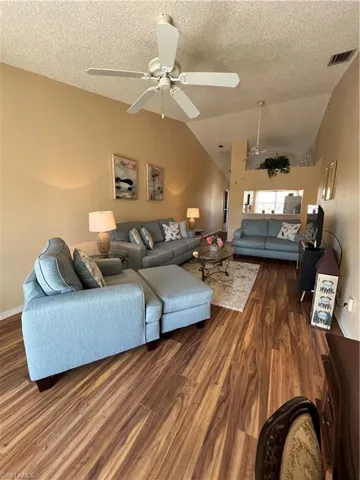 Open concept living area featuring vaulted ceilings, wood-finish flooring, and ceiling fans