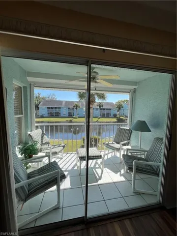 Enclosed patio featuring sliding glass doors, white tiled flooring, a ceiling fan, and a water-facing balcony with metal railings