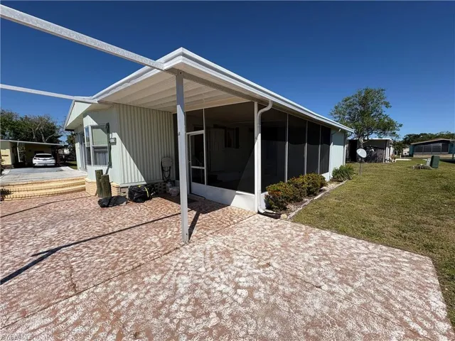 Back of property with a lawn and a sunroom