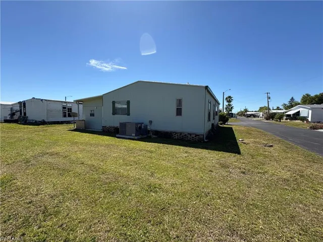 Rear view of property with a lawn and central AC