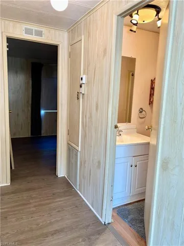 Hallway featuring visible vents, a sink, and wood finished floors