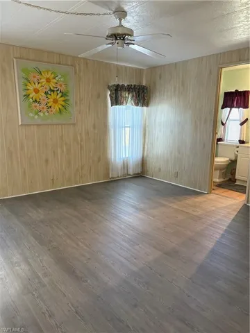Empty room with wood walls, a ceiling fan, and wood finished floors