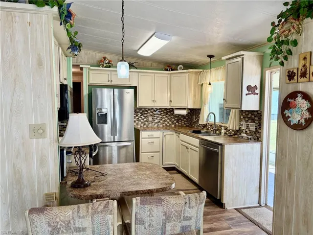 Kitchen with a sink, decorative light fixtures, tasteful backsplash, wood finished floors, and appliances with stainless steel finishes