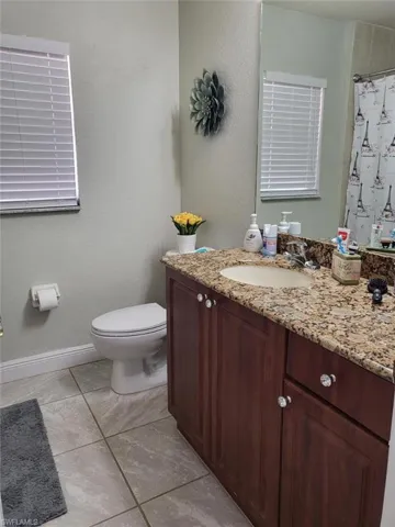 Bathroom featuring vanity, tile patterned flooring, and toilet