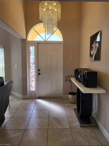 Foyer entrance with a high ceiling, light tile patterned floors, and a chandelier