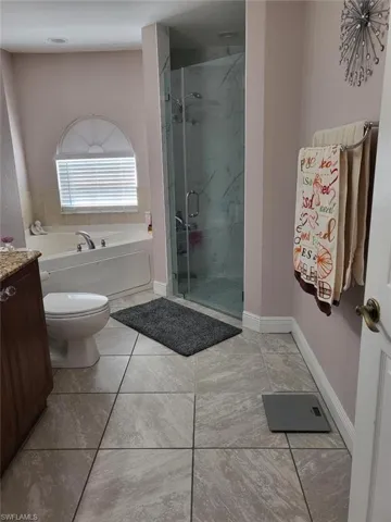Full bathroom with vanity, separate shower and tub, tile patterned flooring, and toilet