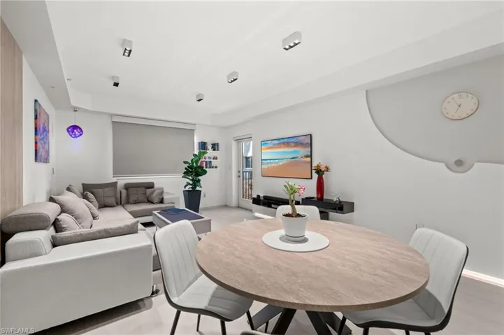 Open-concept living and dining area featuring light-toned flooring, recessed lighting, and a neutral color palette