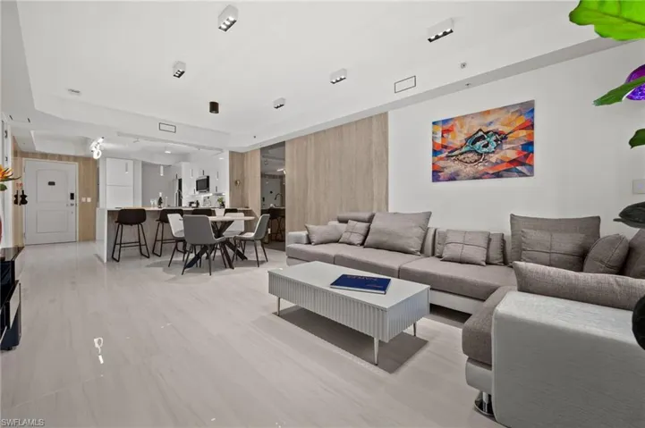 Open-concept living space featuring light-toned flooring, recessed lighting, a modern kitchen with a breakfast bar, and a dining area