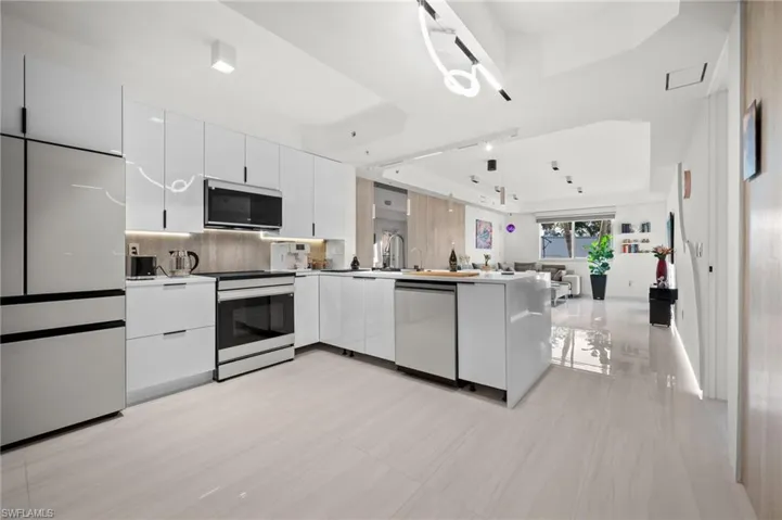 Modern kitchen featuring white high-gloss cabinetry, stainless steel appliances, and wood-finish flooring