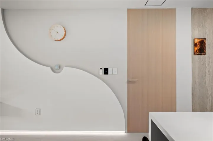 Modern interior wall featuring a light wood-finish door, a curved architectural detail, and an integrated lighting strip at the base