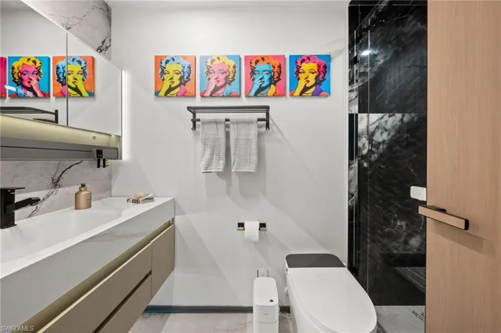 Contemporary bathroom featuring a floating vanity with an integrated sink, a matte black faucet, and a large illuminated mirror