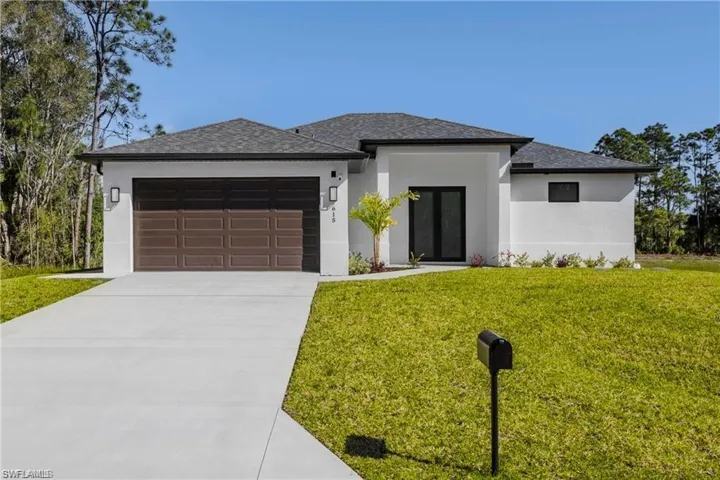 Prairie-style house with stucco siding, a front yard, concrete driveway, a garage, and a shingled roof
