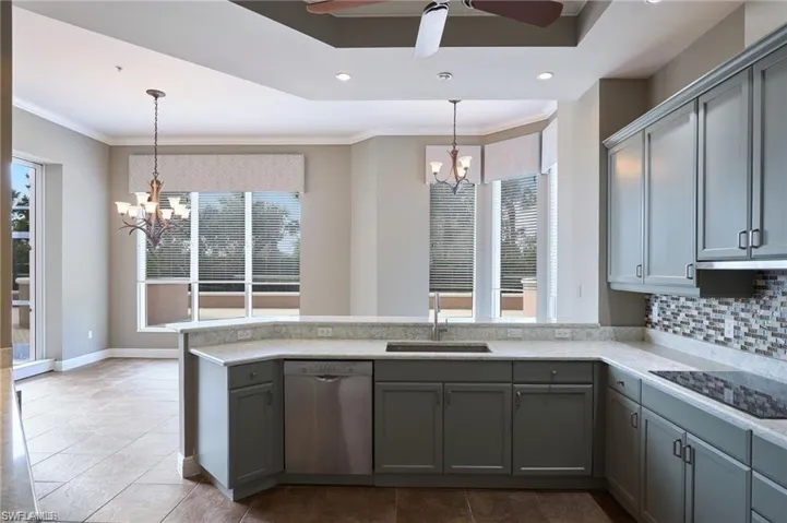 Kitchen with tasteful backsplash, stainless steel dishwasher, ceiling fan with notable chandelier, black electric cooktop, and sink