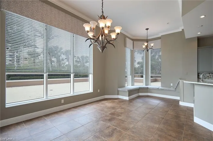 Unfurnished dining area featuring an inviting chandelier, plenty of natural light, ornamental molding, and sink
