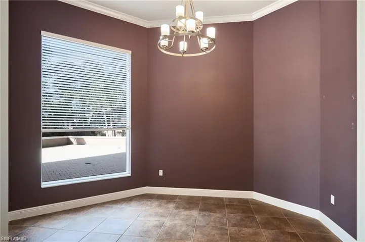 Tiled empty room with ornamental molding and a chandelier