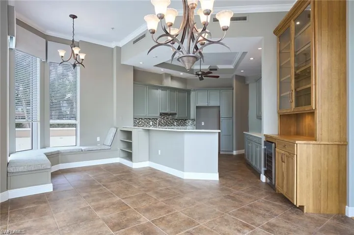Kitchen featuring ceiling fan with notable chandelier, tasteful backsplash, wine cooler, and crown molding