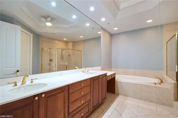 Bathroom featuring vanity, a tray ceiling, ceiling fan, crown molding, and shower with separate bathtub
