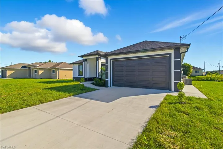 View of front of property with a front yard, concrete driveway, and stucco siding