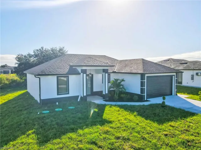 View of front of property with stucco siding, a front lawn, driveway, and a garage