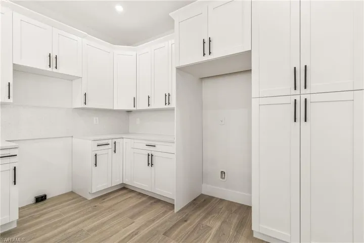 Kitchen featuring white cabinets, light wood finished floors, tasteful backsplash, light stone countertops, and recessed lighting