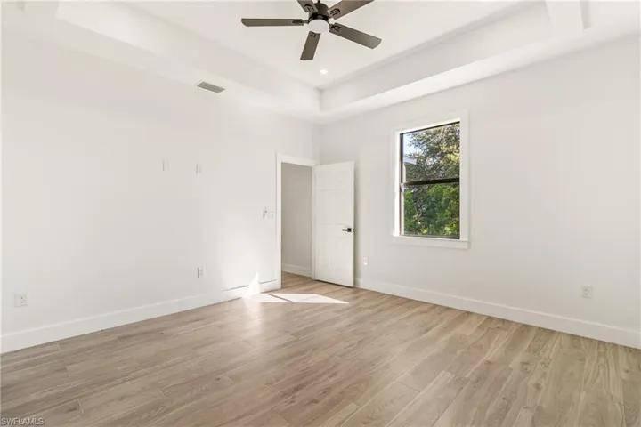 Unfurnished room with a tray ceiling, wood finished floors, and ceiling fan