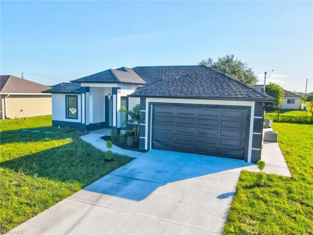 Ranch-style house featuring a front lawn, stucco siding, concrete driveway, and a shingled roof