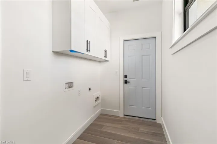 Laundry area featuring electric dryer hookup, cabinet space, dark wood-type flooring, and hookup for a washing machine