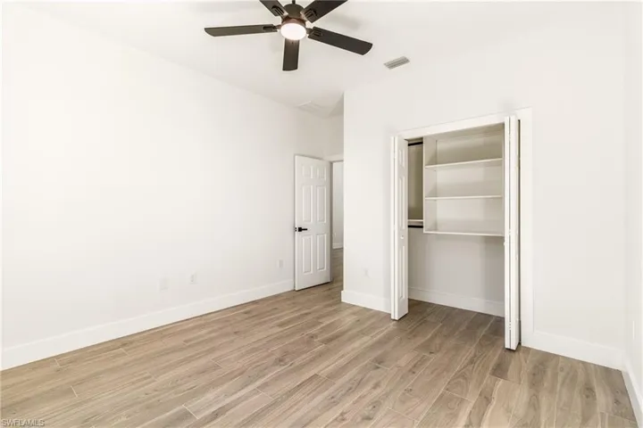 Unfurnished bedroom featuring a closet, light wood-style flooring, and ceiling fan