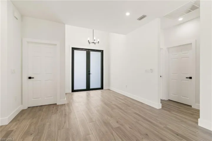 Foyer featuring light wood finished floors, a chandelier, and recessed lighting