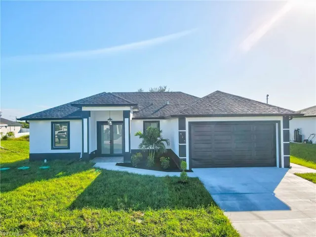 View of front of home featuring stucco siding, a front lawn, concrete driveway, and a shingled roof