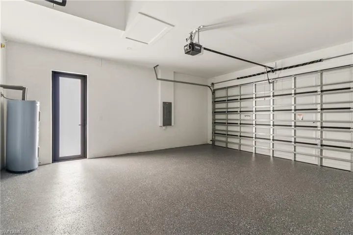 Garage featuring water heater, electric panel, and a garage door opener