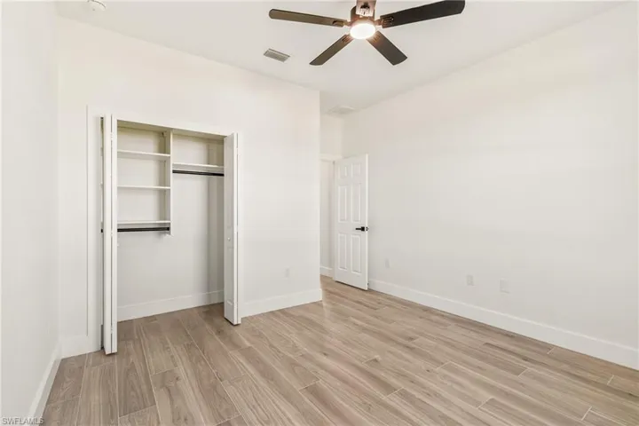 Unfurnished bedroom with light wood-type flooring, a ceiling fan, and a closet