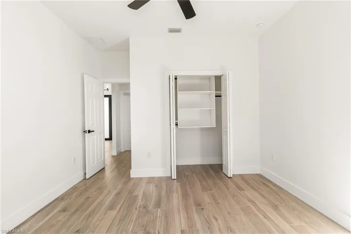 Unfurnished bedroom featuring light wood finished floors, a closet, and ceiling fan