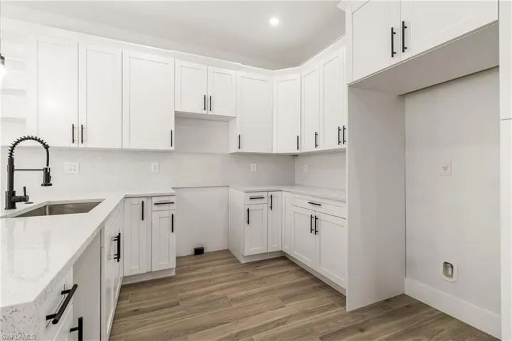 Kitchen with white cabinetry, light wood-type flooring, light stone counters, open shelves, and tasteful backsplash