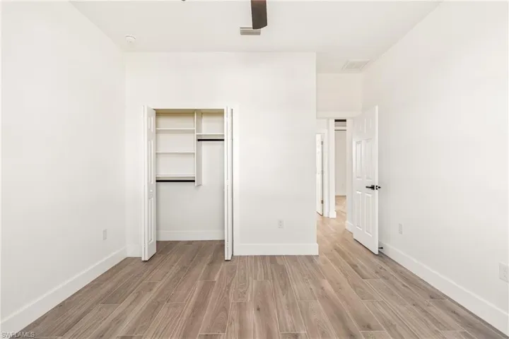 Unfurnished bedroom featuring wood finish floors, a closet, and ceiling fan