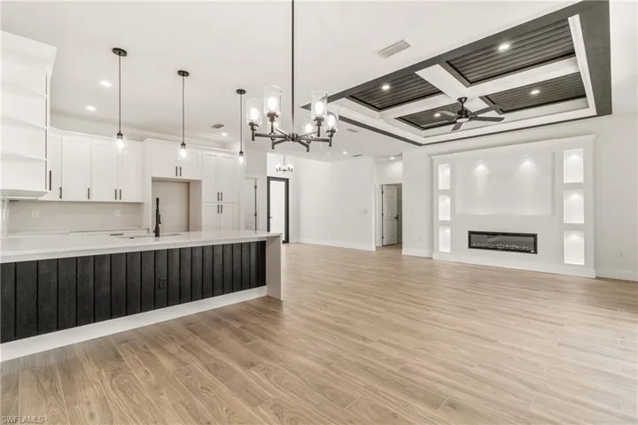 Kitchen with white cabinets, hanging light fixtures, open shelves, a chandelier, and open floor plan