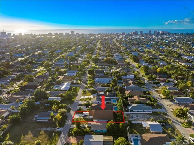 Aerial view of residential area with property parcel outlined, city skyline, and a nearby body of water