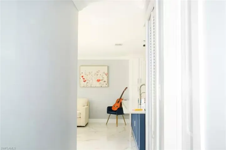 Recessed lighting illuminates a well-appointed wet bar area featuring white upper cabinetry, a stainless steel faucet, and blue lower cabinetry