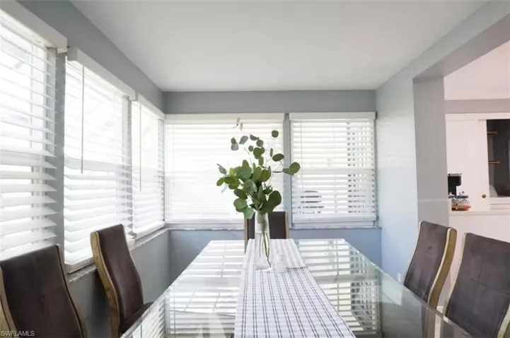 Dining area featuring a corner arrangement of multiple windows with white horizontal blinds, light blue wall paint, and a white ceiling