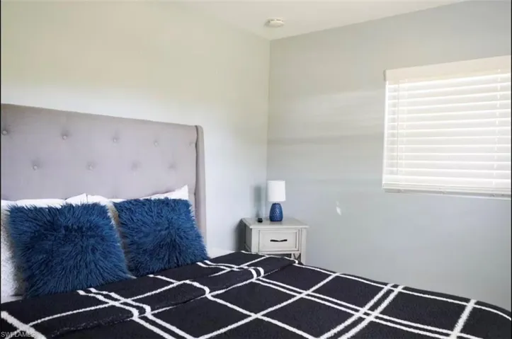 Tufted fabric headboard with a light-colored wood nightstand featuring a single drawer and cabinet space