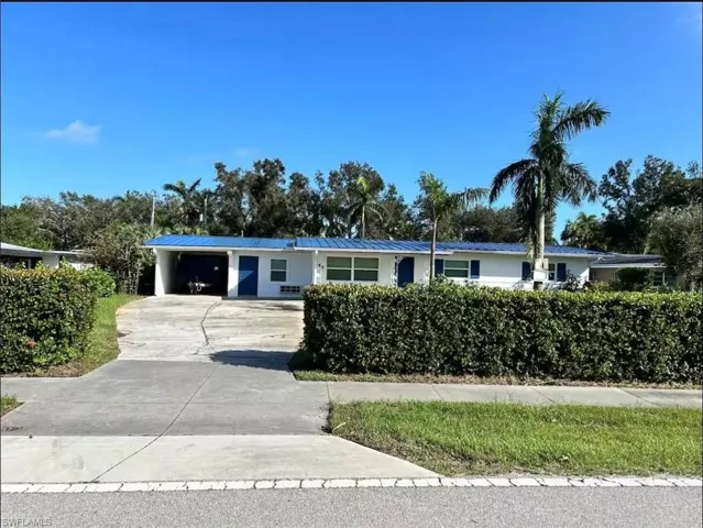 Single-story residence featuring a blue metal roof, white exterior siding, and blue window shutters