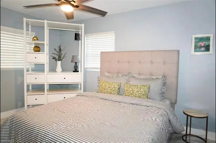 Room with light blue walls, featuring a ceiling fan with integrated lighting, window blinds, and wood-finish flooring