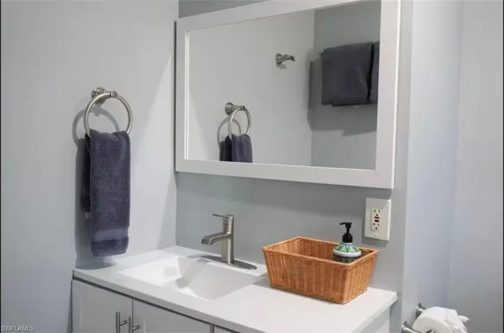 Bathroom vanity featuring a white rectangular sink with a single-handle brushed nickel faucet, set into a white countertop
