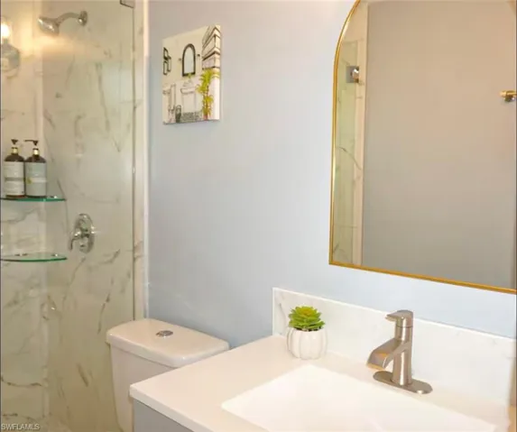 Shower featuring glass enclosure, wall-mounted shower head, and two corner glass shelves