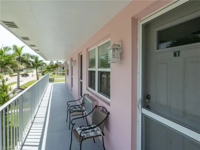 Covered exterior balcony with pale pink stucco facade