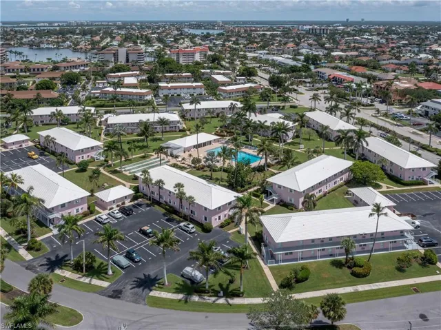 Aerial perspective showcasing a residential community with multiple two-story buildings featuring white roofs and light pink facades