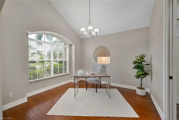 Home office/formal dining room featuring lofted ceiling, hanging lights, and dark wood-style floors