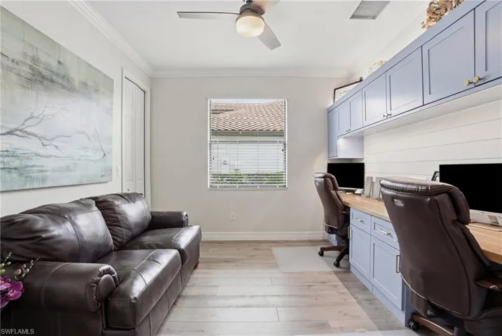 Office area featuring light wood-type flooring, a ceiling fan, built in desk, and crown molding