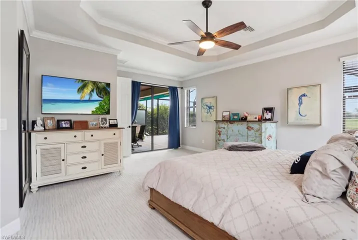 Bedroom with access to outside, light colored carpet, a raised ceiling, ceiling fan, and ornamental molding